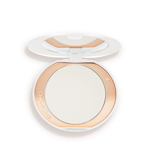 An open, setting powder compact with a mirrored-lid and white and gold-coloured packaging.