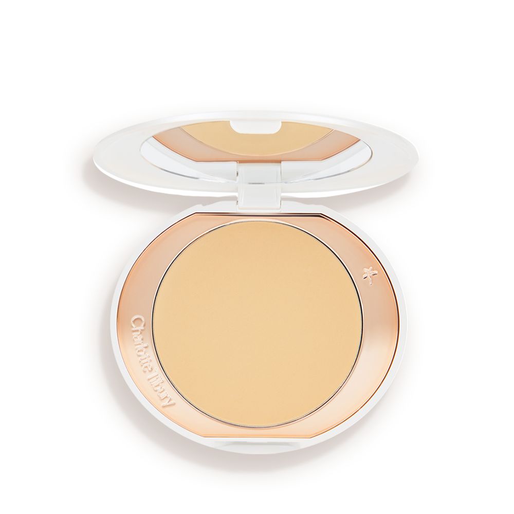 An open, setting powder compact with a mirrored-lid and white and gold-coloured packaging.