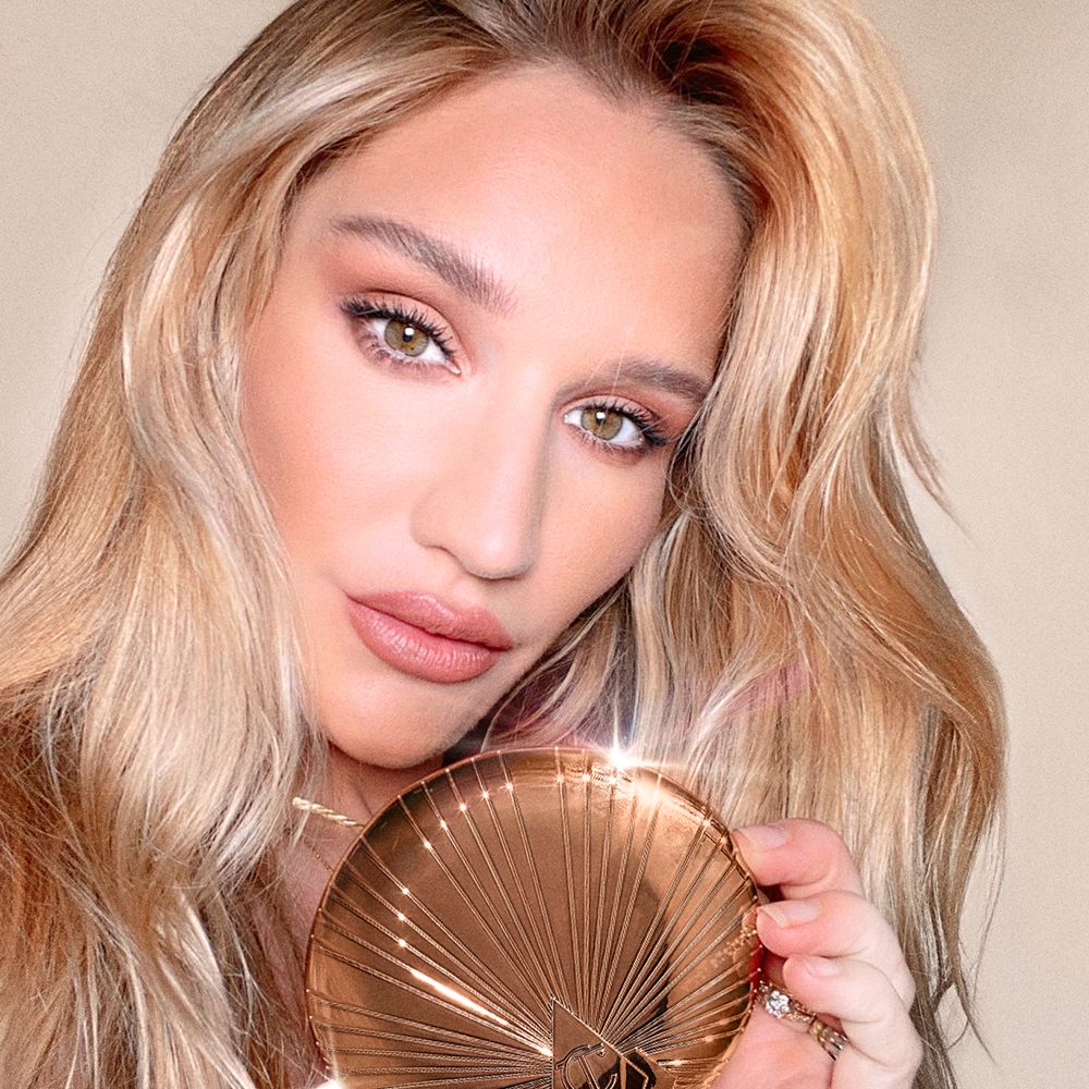 Sofia Tilbury holding a bronzer compact in dark golden packaging with a starburst pattern on the outside.
