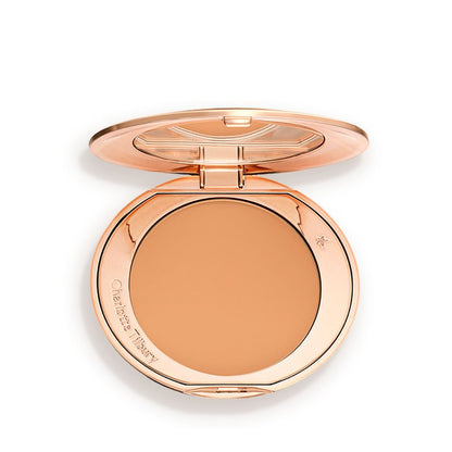 An open, pressed powder compact in a sandy-brown shade.