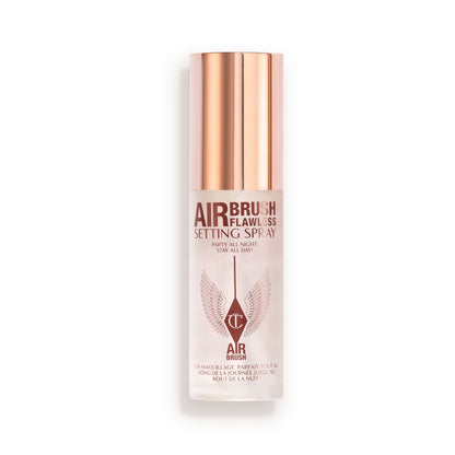 A closed, travel-size setting spray in a clear bottle with a gold-coloured lid.