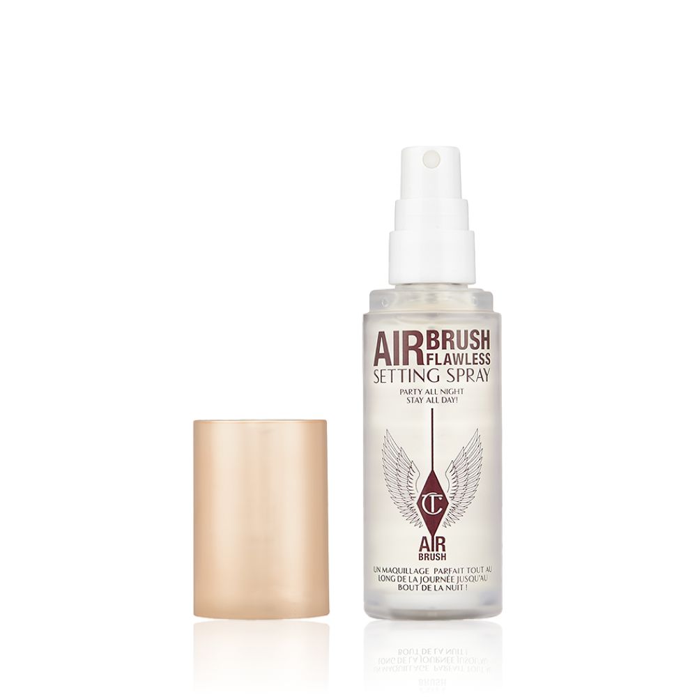 An open, travel-size setting spray in a clear bottle with a gold-coloured lid.
