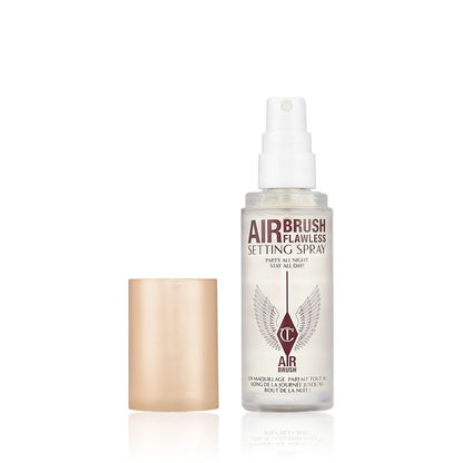 An open, travel-size setting spray in a clear bottle with a gold-coloured lid.