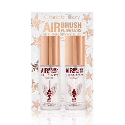 Two, identical, mini setting sprays with gold-coloured lids and their white and gold-coloured packaging box behind them with gold stars printed all over with text on the box that reads, 'Charlotte Tilbury. Airbrush Flawless Setting Spray duo'