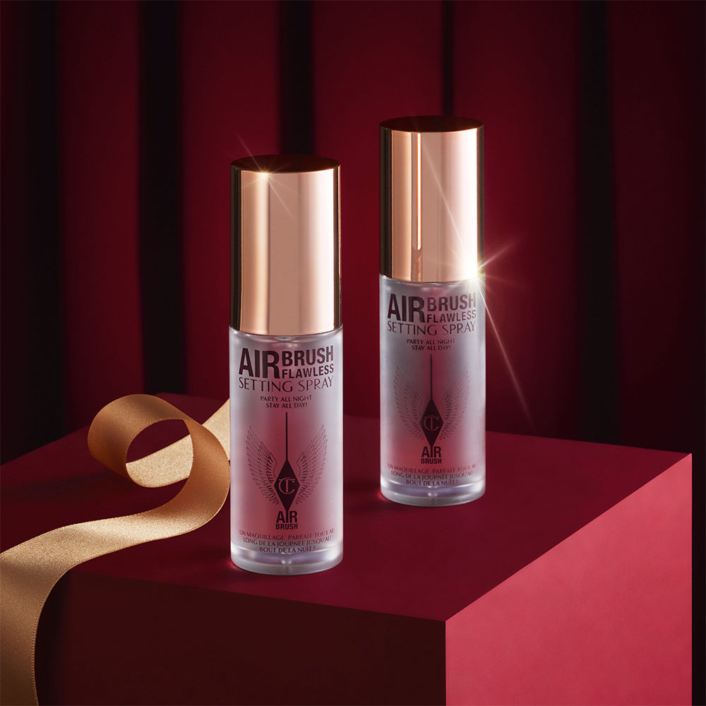Two, identical mini, setting sprays in clear bottles with gold-coloured lids.