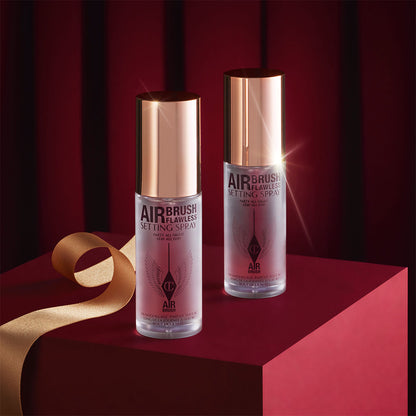 Two, identical mini, setting sprays in clear bottles with gold-coloured lids.