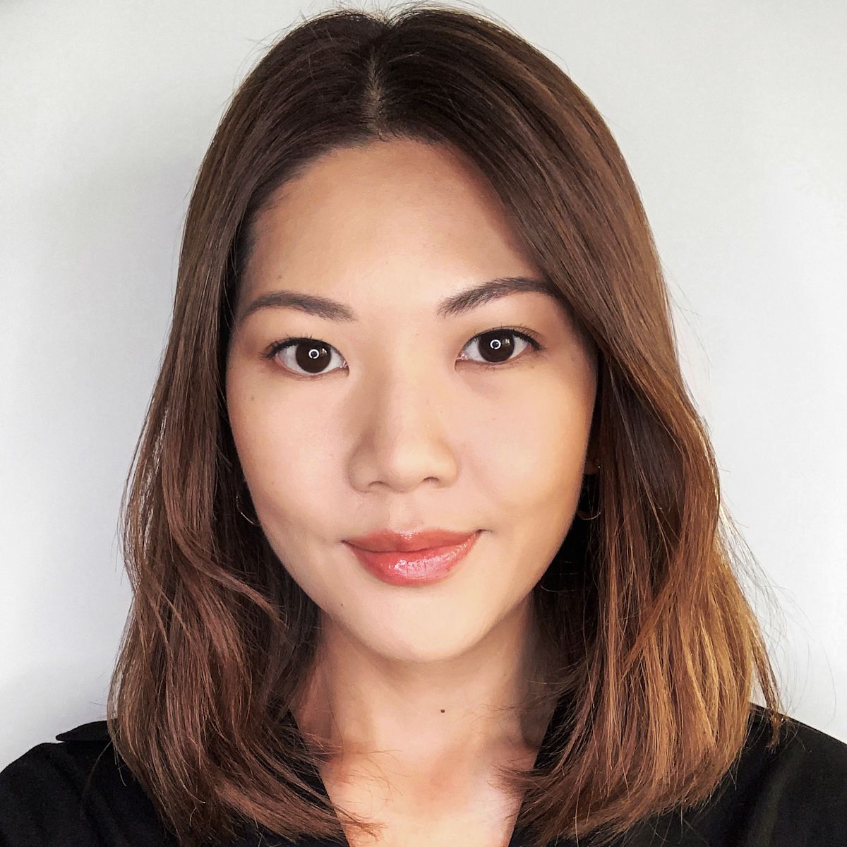 A fair-tone model wearing coral lipstick and smokey eye makeup along with a pressed powder in light beige colour that makes her skin looks matte and flawless.