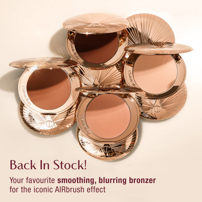 Five open compacts of Charlotte Tilbury bronzer with rose gold packaging, arranged in a circular pattern. Text reads 'Back In Stock! Your favourite smoothing, blurring bronzer for the iconic AIRbrush effect.