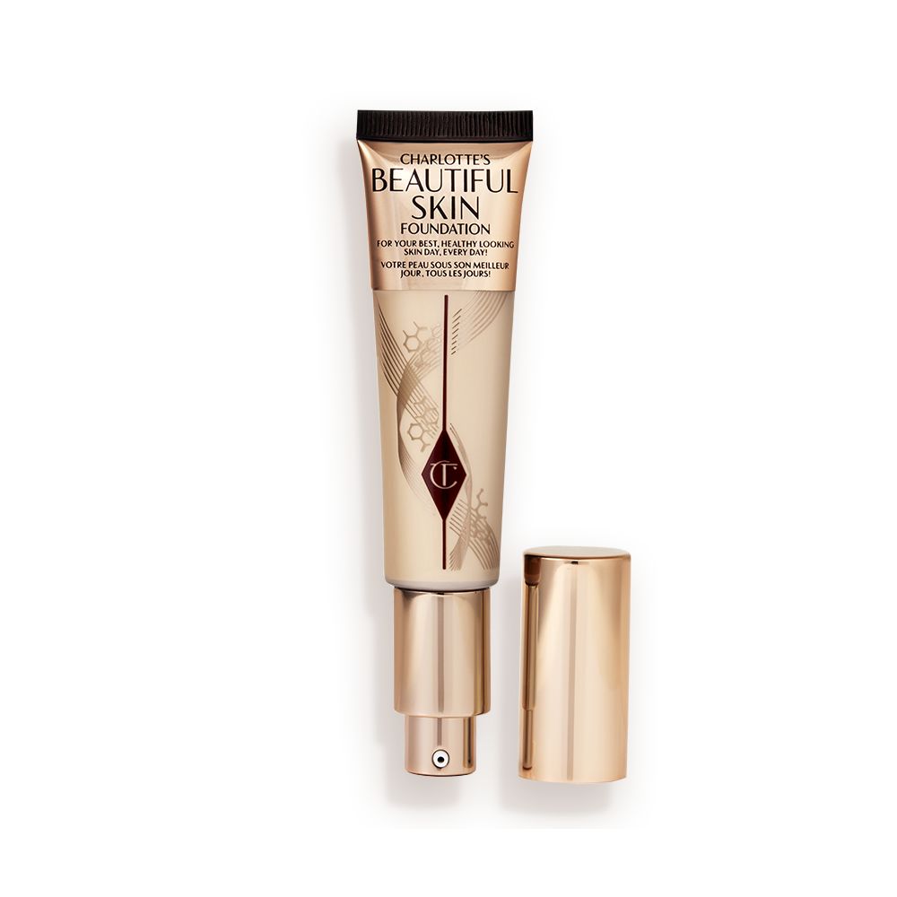 An open foundation wand in gold packaging with a pump dispenser and a medium-beige-coloured body to show the shade of the foundation inside.