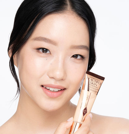 Fair-tone brunette model wearing glowy, skin-like foundation with a satin finish with nude lipstick and subtle eye makeup.