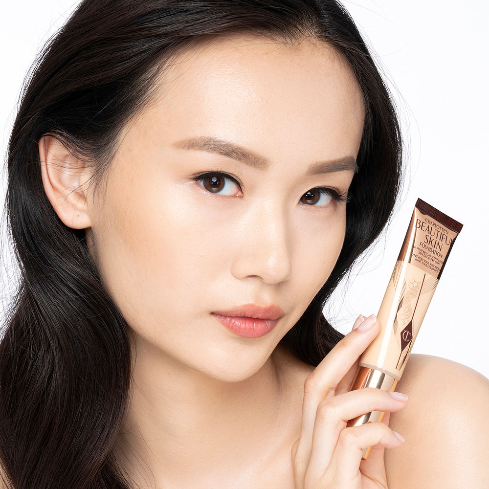 Fair-tone brunette model wearing glowy, skin-like foundation with a satin finish with nude lipstick and subtle eye makeup.