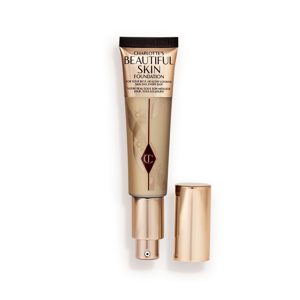 An open foundation wand in gold packaging with a pump dispenser and a medium-brown-coloured body to show the shade of the foundation inside.