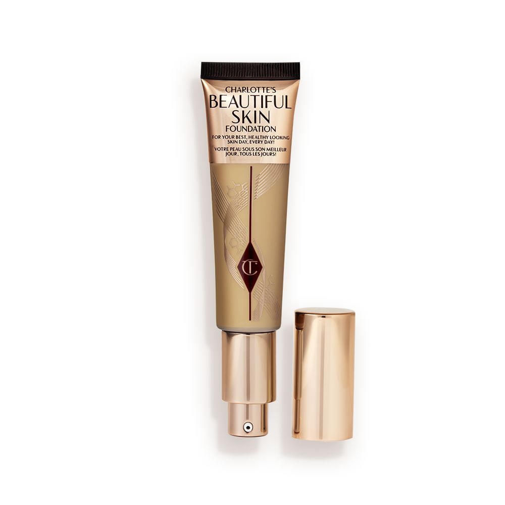 An open foundation wand in gold packaging with a pump dispenser and a medium-brown-coloured body to show the shade of the foundation inside.