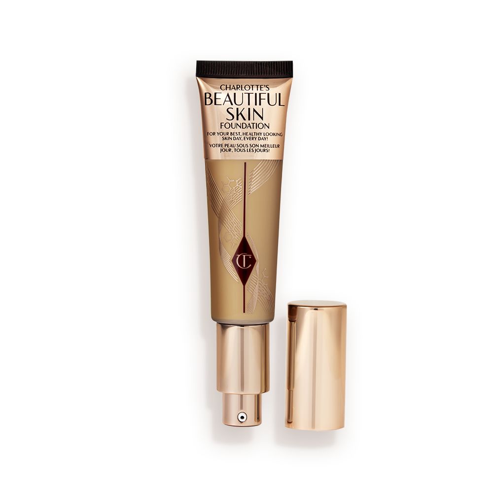 An open foundation wand in gold packaging with a pump dispenser and a medium-dark-brown-coloured body to show the shade of the foundation inside.
