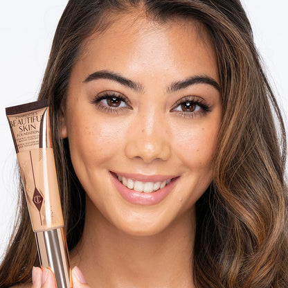 Medium-light-tone brunette model wearing glowy, skin-like foundation with a fresh, satin finish with a nude lipstick, and subtle eye makeup.