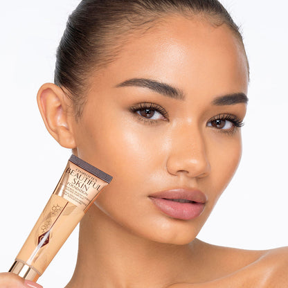 Deep-tone model with glowy, flawless skin, wearing skin-like foundation that adds a youthful glow and looks natural along with nude pink lipstick and subtle everyday eye makeup.
