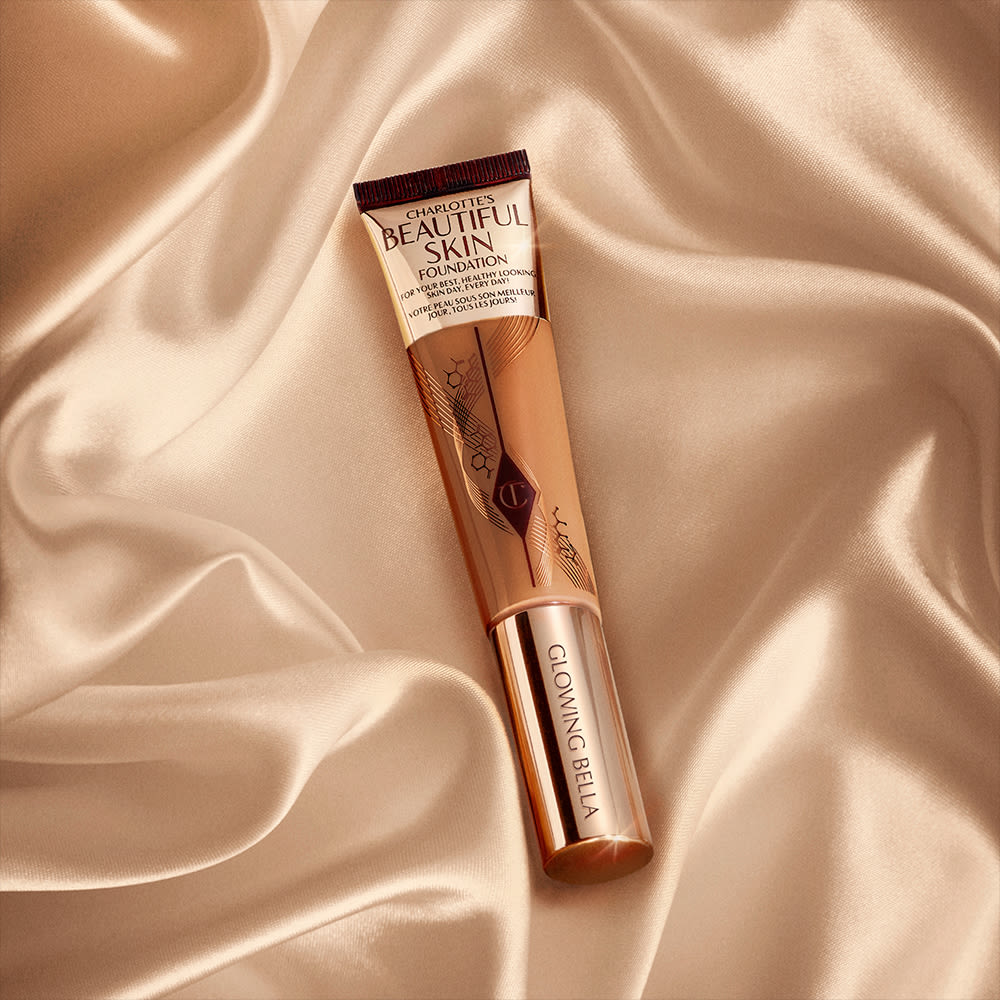 A foundation wand in gold, engraved packaging with a medium-dark-brown-coloured body to show the shade of the foundation inside.