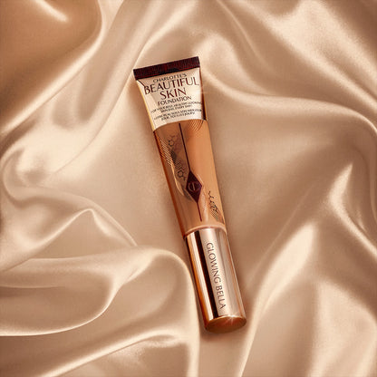 A foundation wand in gold, engraved packaging with a medium-dark-brown-coloured body to show the shade of the foundation inside.