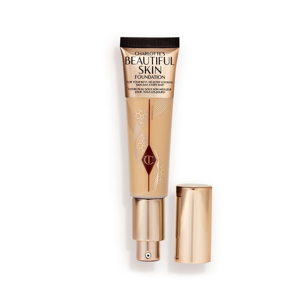 An open foundation wand in gold packaging with a pump dispenser and a dark-sandy-brown-coloured body to show the shade of the foundation inside.