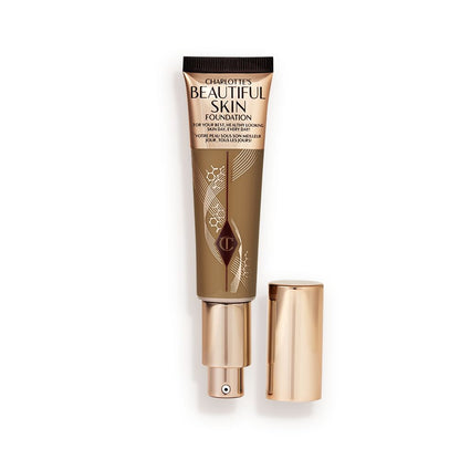 An open foundation wand in gold packaging with a pump dispenser and a dark-brown-coloured body to show the shade of the foundation inside.