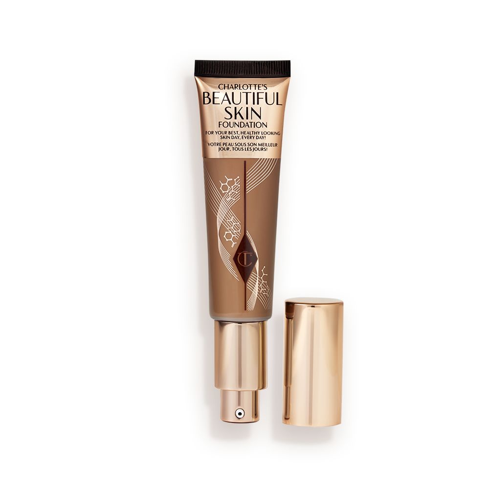 An open foundation wand in gold packaging with a pump dispenser and a dark-brown-coloured body to show the shade of the foundation inside.