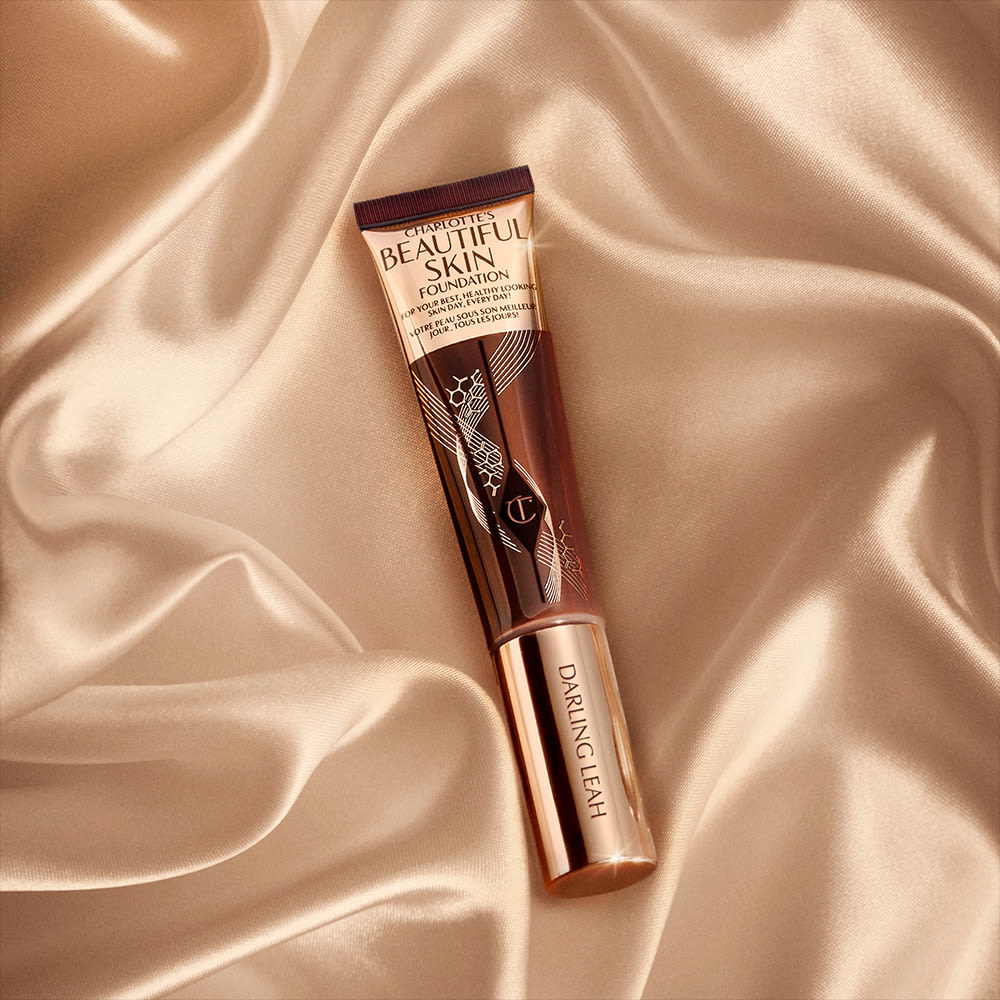A foundation wand in gold, engraved packaging with a dark-brown-coloured body to show the shade of the foundation inside.