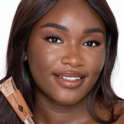 Deep-tone brunette model with brown eyes wearing nude pink lipstick with a skin-like foundation with a flawless, dewy finish.