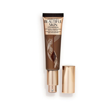 An open foundation wand in gold packaging with a pump dispenser and a dark-brown-coloured body to show the shade of the foundation inside.