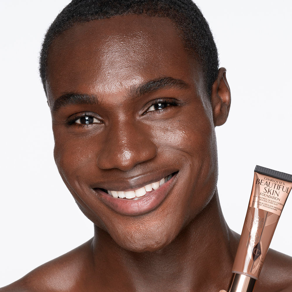 Deep-tone male brunette model with brown eyes wearing a skin-like foundation with a flawless, dewy finish.