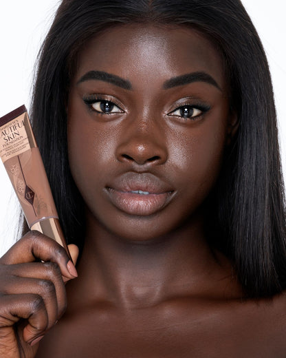Deep-tone brunette model with brown eyes wearing nude pink lipstick with a skin-like foundation with a flawless, dewy finish.
