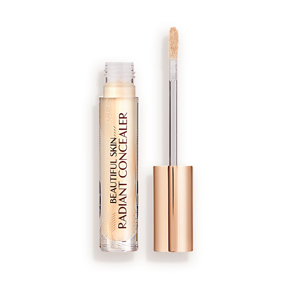 Light beige radiant concealer in a glass tube with its gold-coloured lid with a doe-foot end next to it, and text on the tube that reads, 'Beautiful Skin Concealer'