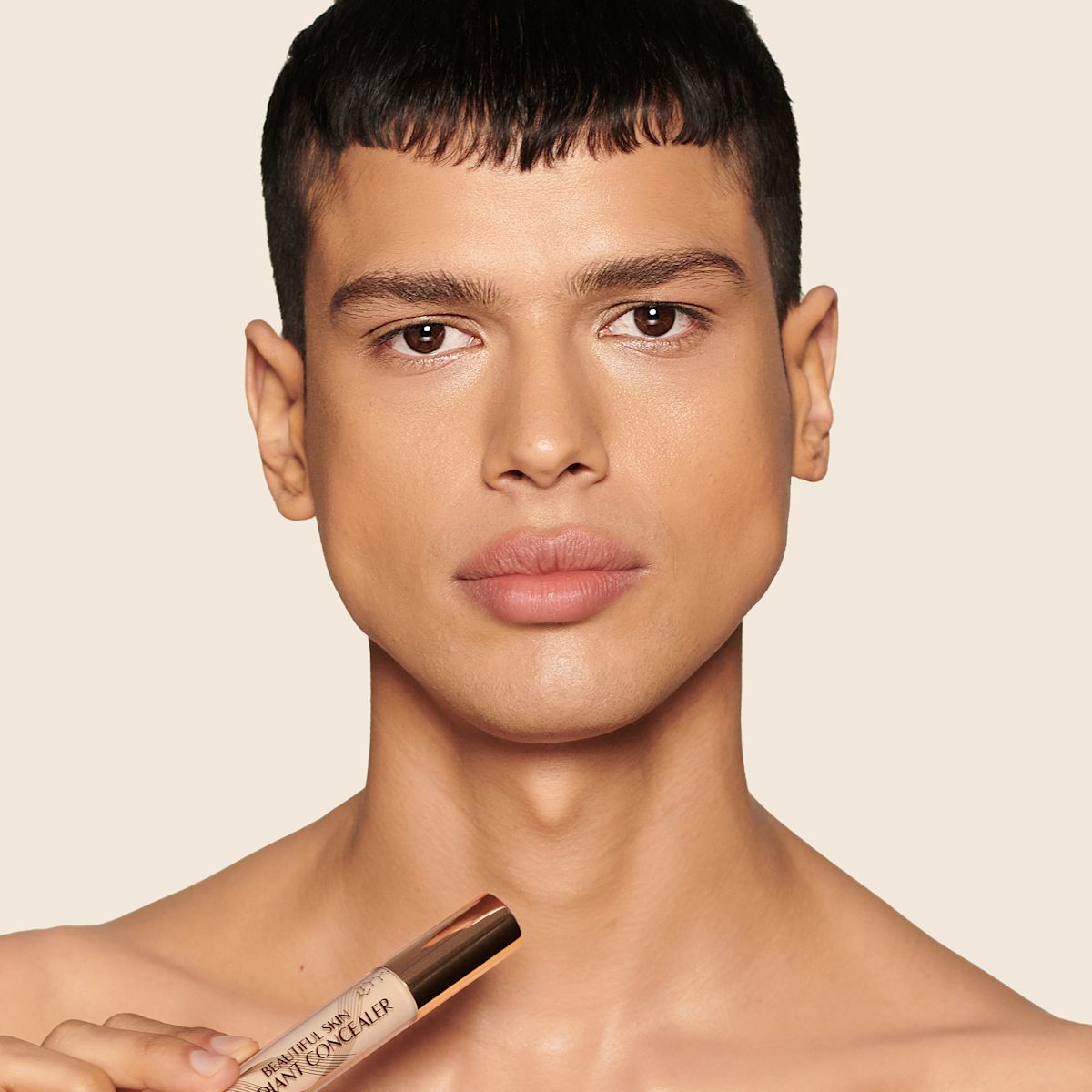 Medium-tone model with brown eyes wearing a radiant, concealer that brightens, covers blemishes, and makes her skin look fresh along with nude lip gloss and subtle eye makeup.