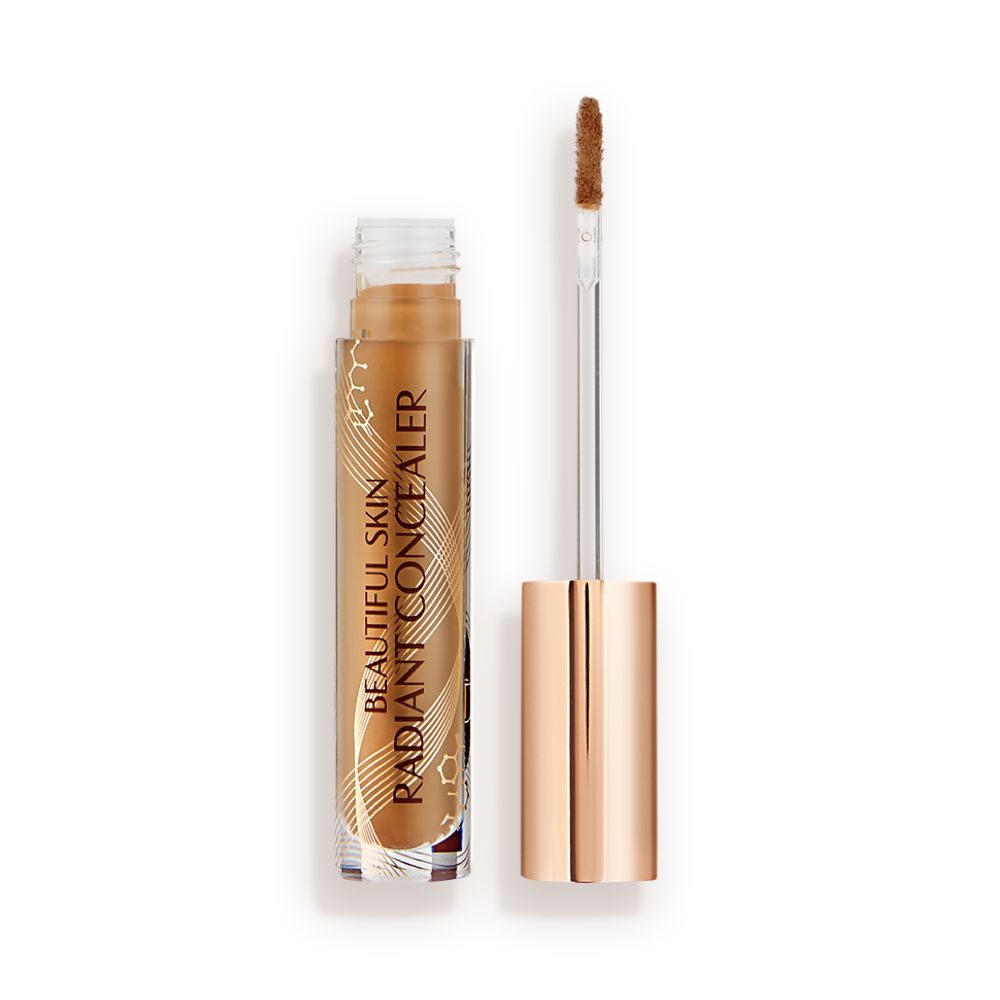 An open concealer in a dark brown shade in a glass tube with its doe-foot applicator next to it.