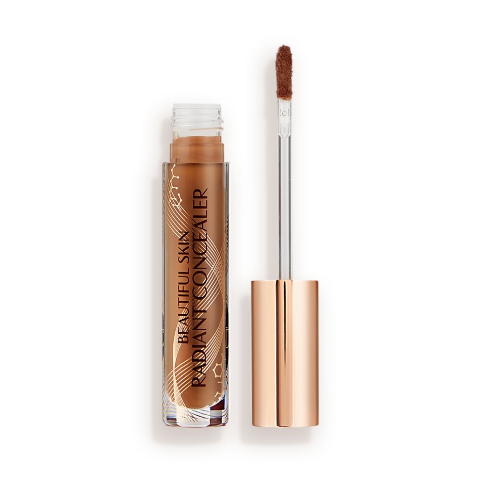 Dark brown radiant concealer in a glass tube with its gold-coloured lid with a doe-foot end next to it, and text on the tube that reads, 'Beautiful Skin Concealer'
