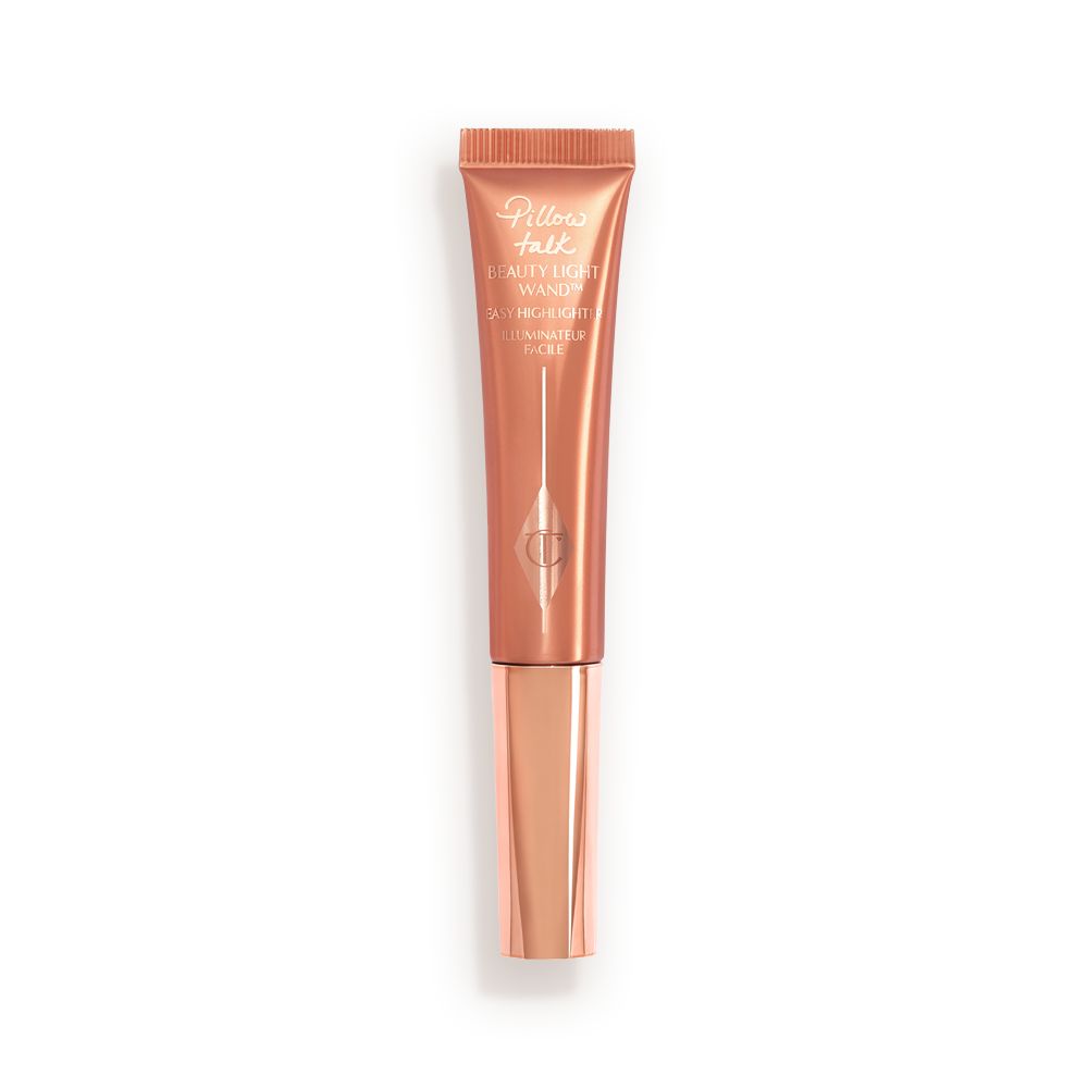 a highlighter wand, packaged in a reflective, peachy-pink tube with a rose gold cap.