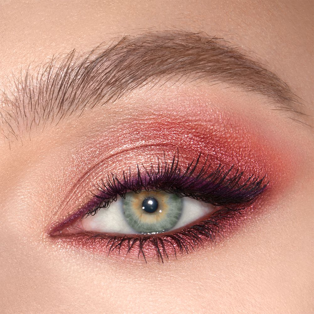 Close-up of a shimmery, peach, plum, and champagne eye look on a fair-tone model with green eyes.
