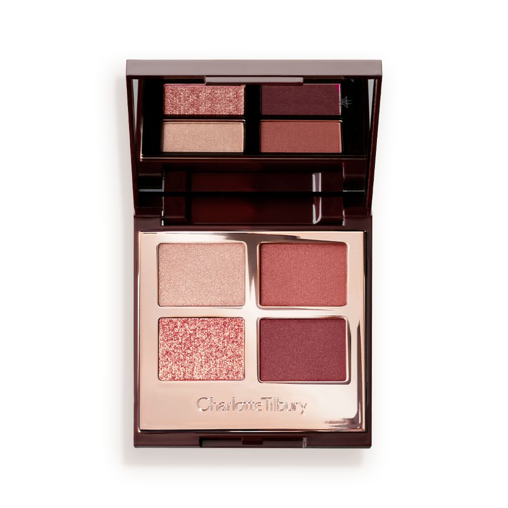 An open, mirrored-lid eyeshadow palette in shades of rose gold, champagne, maroon, and redwood.