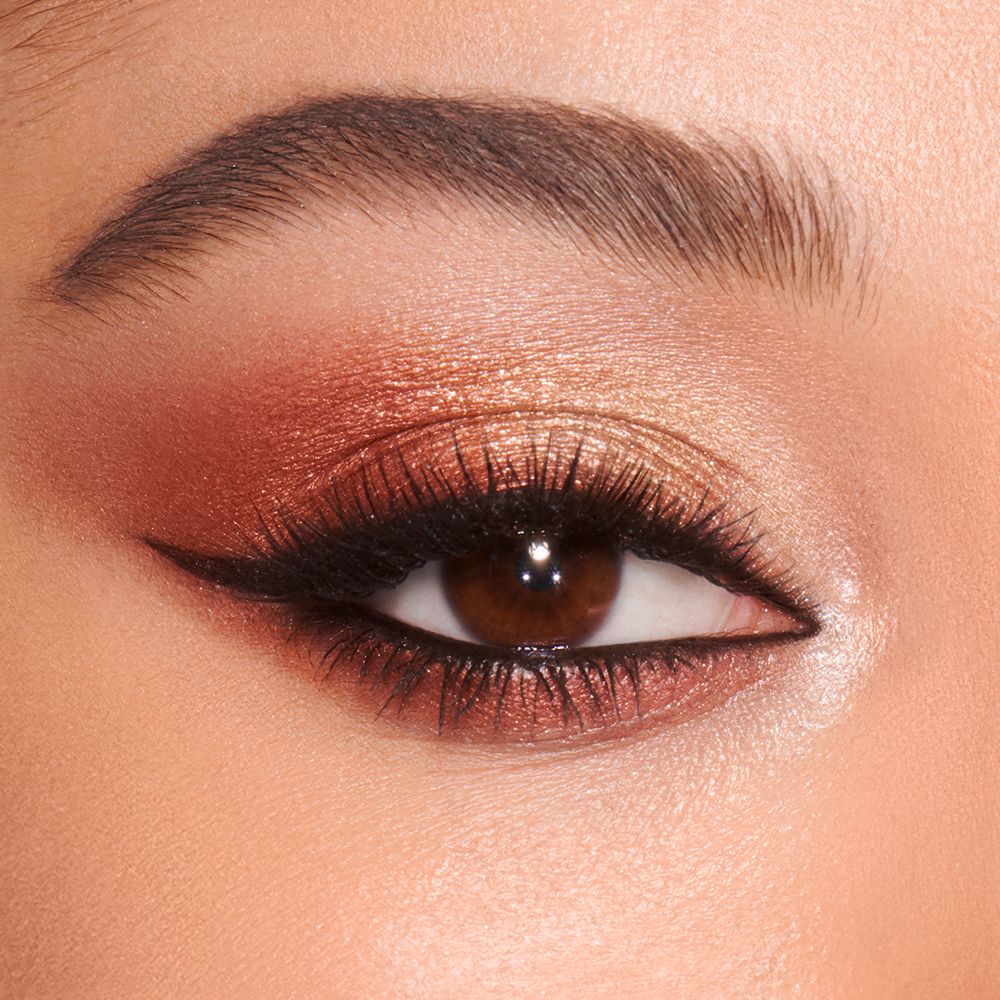 Close-up of a light-tone model's brown eyes with shimmery copper, gold, and brown eye makeup.
