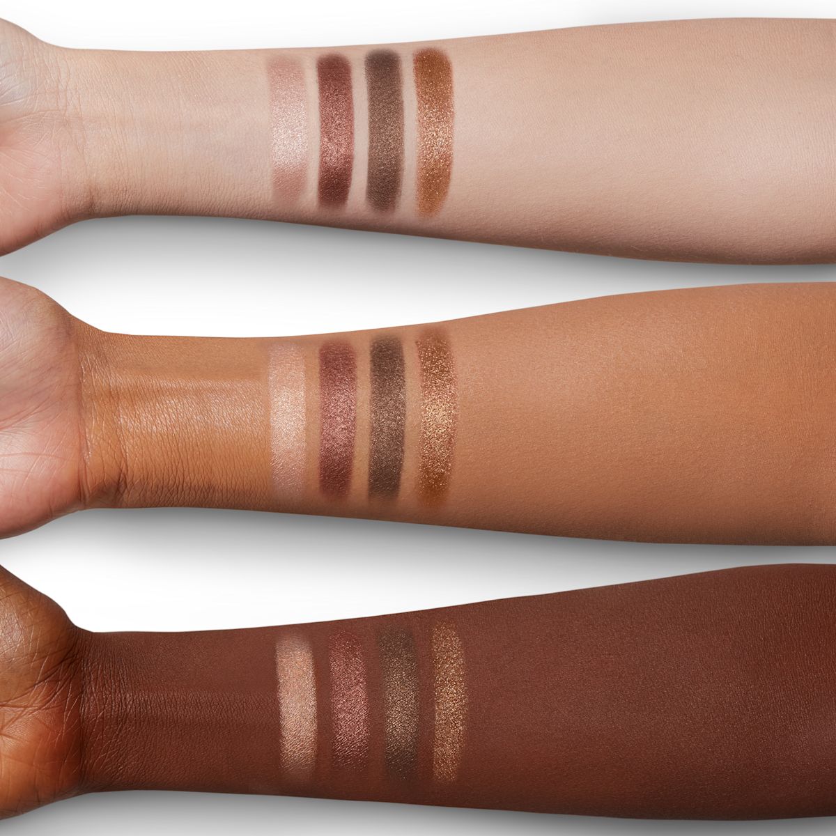 Arm swatches of four sparkly eyeshadows in bronze and copper shades on fair, tan, and deep skin.