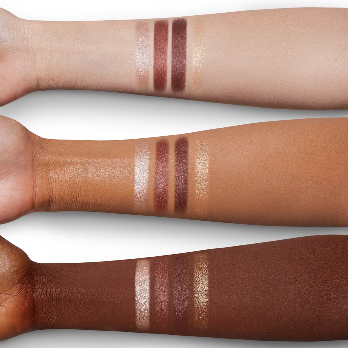 Arm swatches of four matte and shimmery eyeshadows in purple, nude, and golden colours on fair, tan, and deep skin.