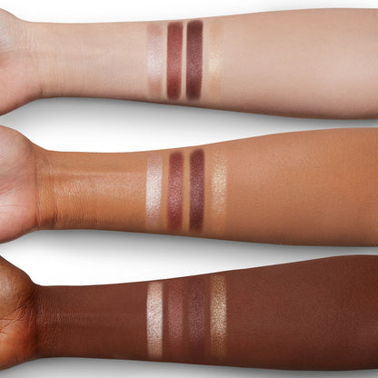 Arm swatches of four matte and shimmery eyeshadows in purple, nude, and golden colours on fair, tan, and deep skin.