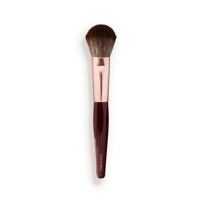 A bronzer and blush brush with soft bristles and rose gold and dark crimson handle.