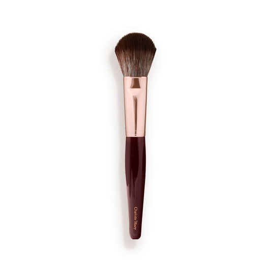 A bronzer and blush brush with soft bristles and rose gold and dark crimson handle.