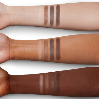 Arm swatches of four matte eyeshadows in cream, tan, taupe, and chocolate colours on fair, tan, and deep skin.