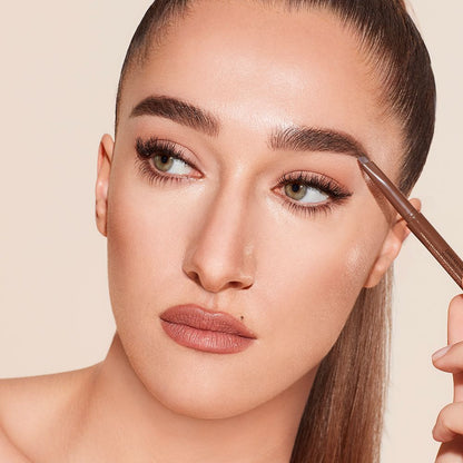 A light-tone model with green eyes wearing smoked-out black eyeliner and filling out her eyebrows with a natural brown-coloured eyebrow pencil.