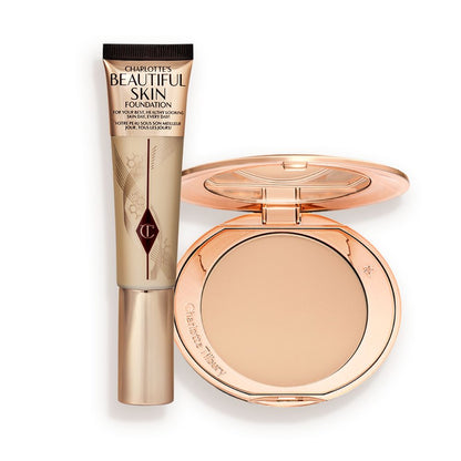 A foundation wand in gold packaging with a brown-beige-coloured body to show the shade of the foundation inside, and a pressed powder compact with a mirrored lid.