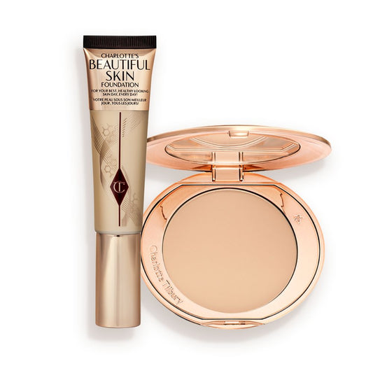 A foundation wand in gold packaging with a brown-beige-coloured body to show the shade of the foundation inside, and a pressed powder compact with a mirrored lid.