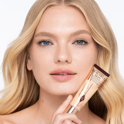 Light-tone blonde model wearing glowy, skin-like foundation with a satin finish with nude lipstick and subtle eye makeup.