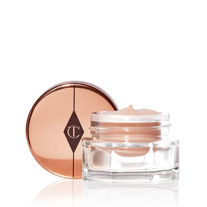 An open, light champagne-coloured eye cream in a glass pot with its rose-gold-coloured lid next to it.