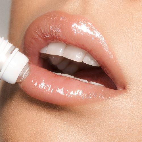 Close-up of a light-tone model applying a nourishing, clear lip oil with a crystal roller ball applicator.